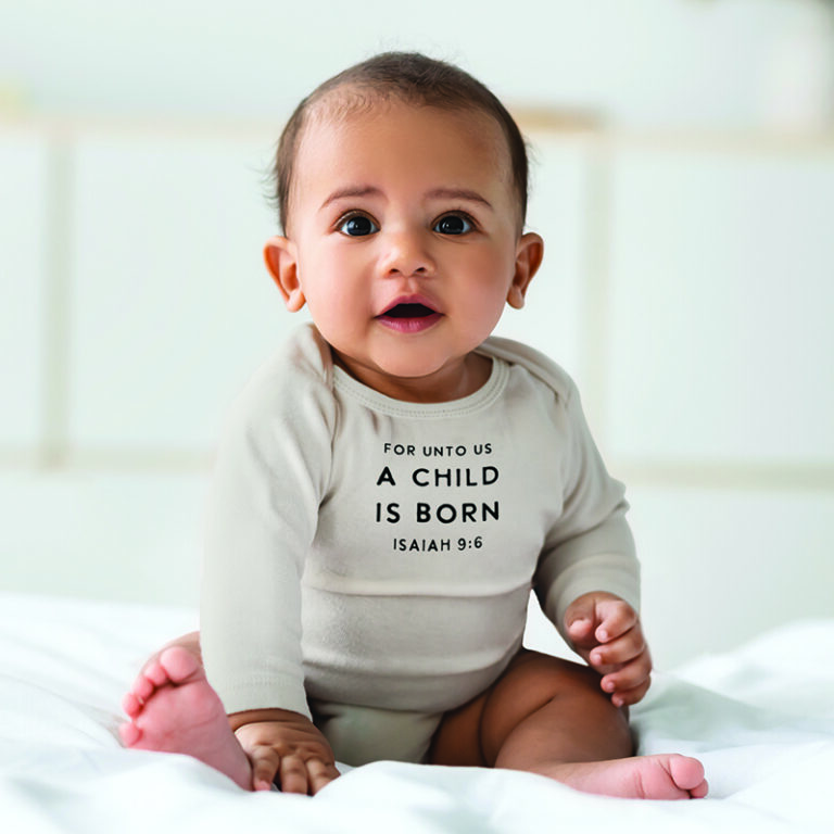 Stephan Baby Children Beauty. Portrait of cute small African American baby sitting on bed on the white blanket at home. Adorable black child wearing bodysuit. Free copy space, selective focus, blurred background